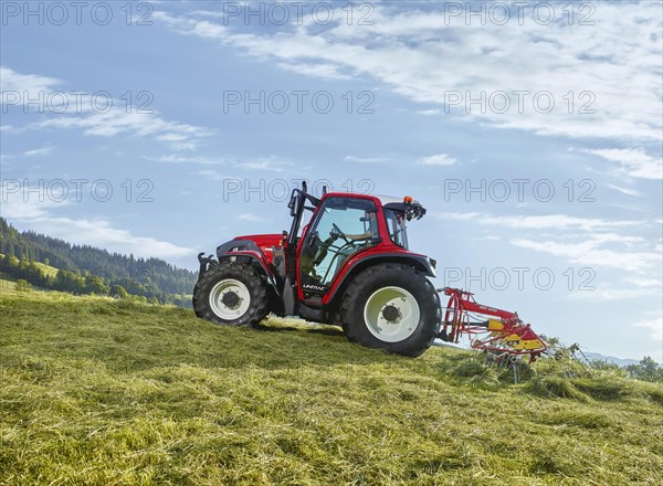 Tractor tedding the freshly cut hay with a tedder