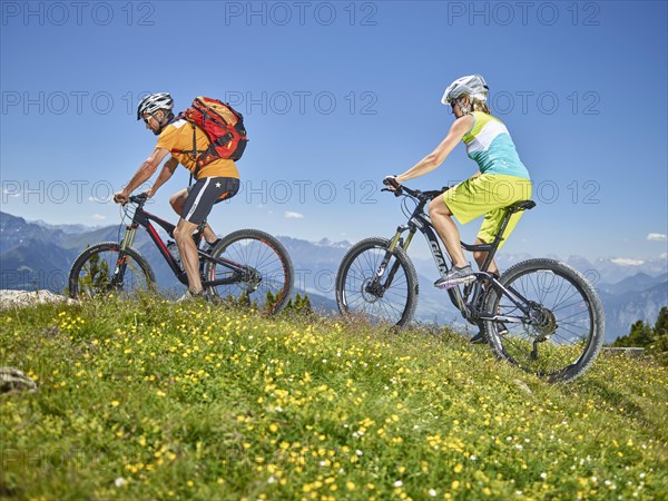 Man 40-45 years and woman 35-40 years with helmets cycle with their mountain bikes