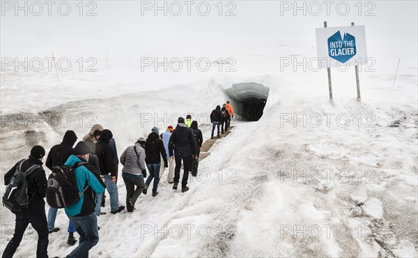 Tourists walking in to glacial cave