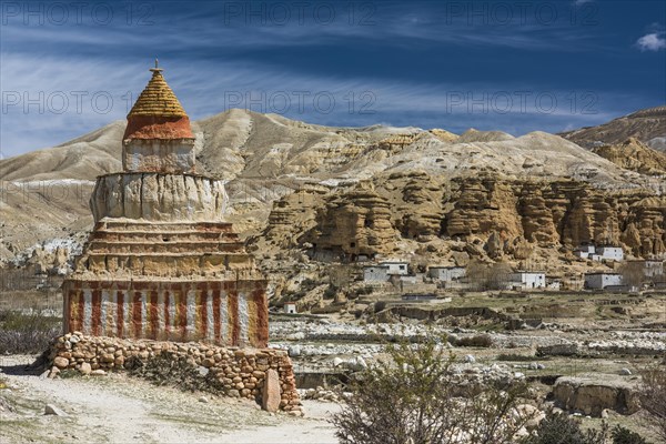 Colourfully painted Buddhist stupa in front of mountain landscape