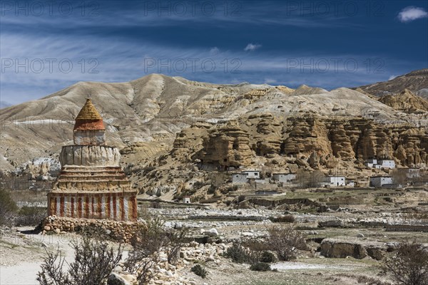 Colourfully painted Buddhist stupa in front of mountain landscape