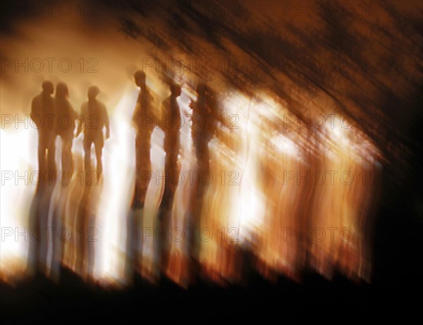 Shadowy outlines of several people in front of fire