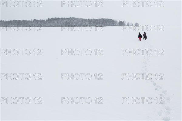 Two people walking over a frozen lake in the Arctic Circle
