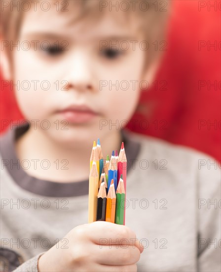 Serious looking girl holding coloured pencils in her hand