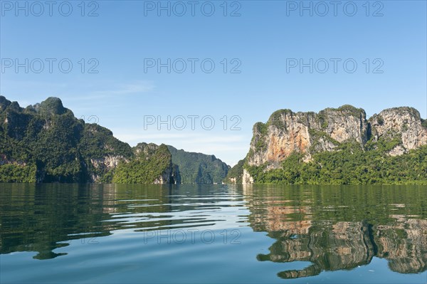 Forested karst limestone mountains reflected in the water