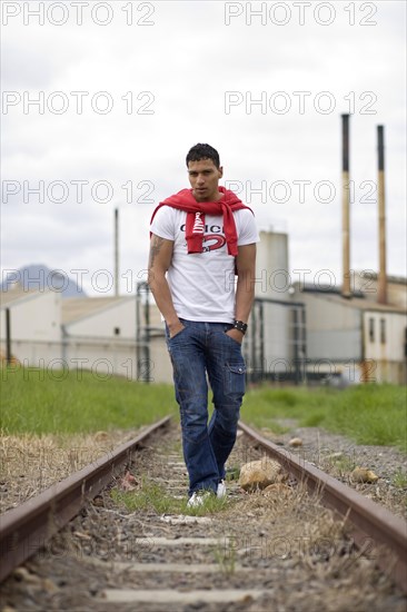 Young man walking on deserted railway