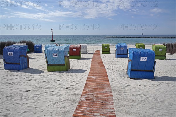 Wooden walkway between colourful beach chairs