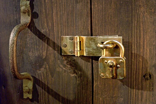 Old wooden door locked with metal fittings and a padlock