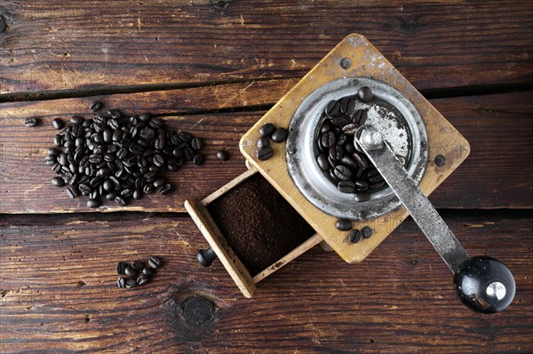 Old coffee grinder with coffee beans on a wooden surface