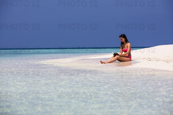 Woman with a book sitting on the beach