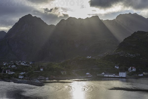 Sun rays breaking through the clouds over the mountains of the municipality of Moskenes