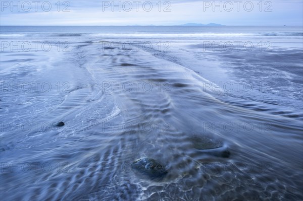 Stream flows over the beach into the sea at low tide