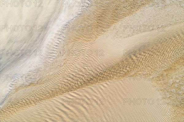 Water flows over a sandy beach at low tide