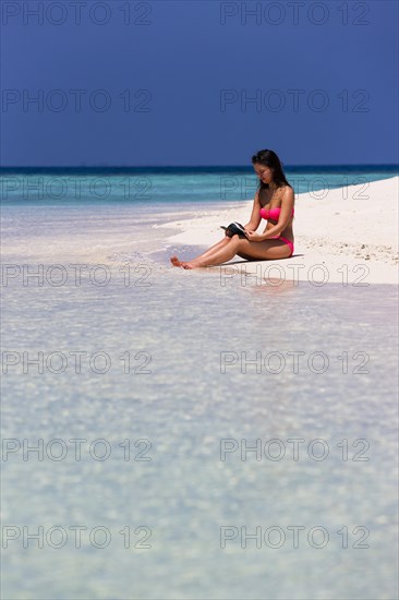 Woman with a book sitting on the beach