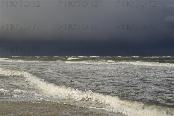 Waves on a sandy beach in front of a rain front over the North Sea