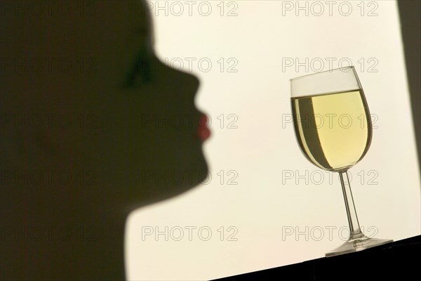 Silhouette in front of a glass with white wine