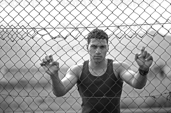 Young man holding onto a fence