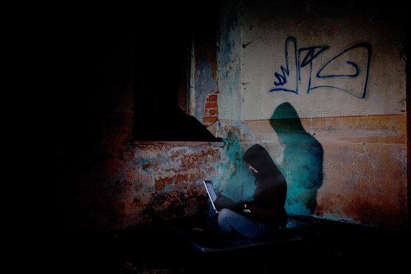Female computer hacker sitting with a laptop in the dark