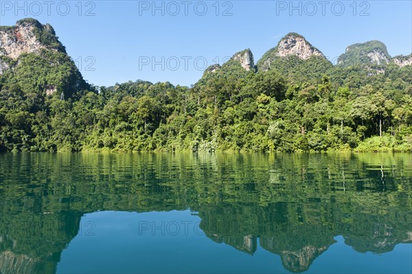 Forested karst limestone mountains with jungle vegetation reflected in the water