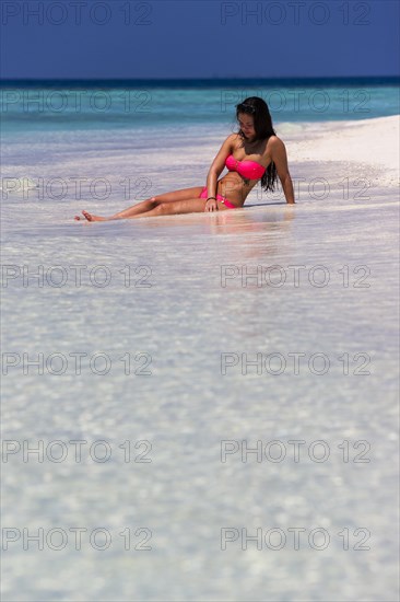 Woman in a pink bikini lying on the beach