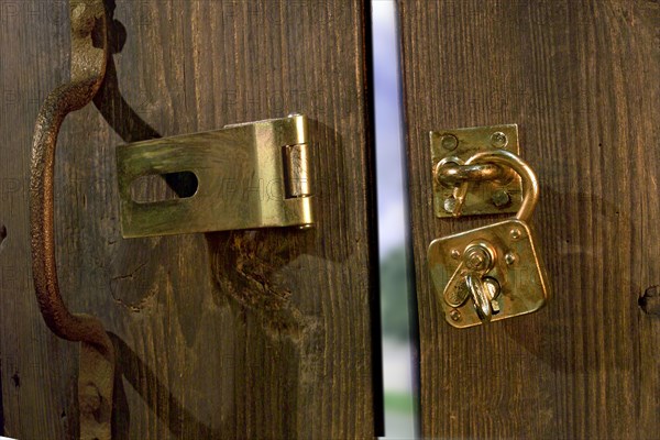 Old wooden door with metal fittings and an open padlock