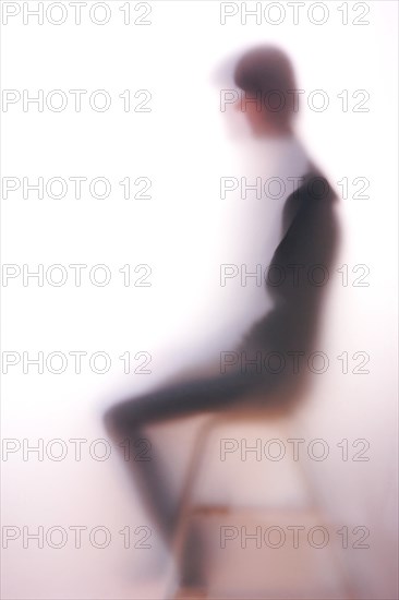 Silhouette of a seated woman behind frosted glass