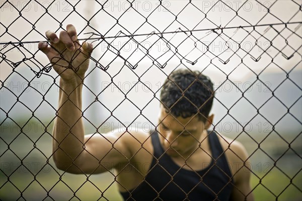 Young man holding onto a fence