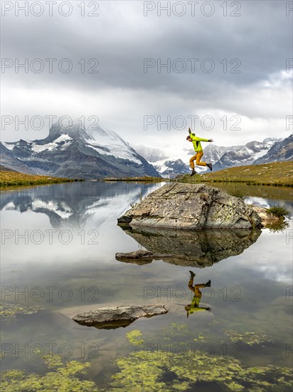 Hiker jumps on rocks in the lake