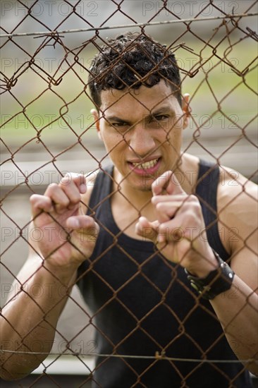 Young man holding onto a fence