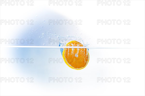 A slice of orange falling into water