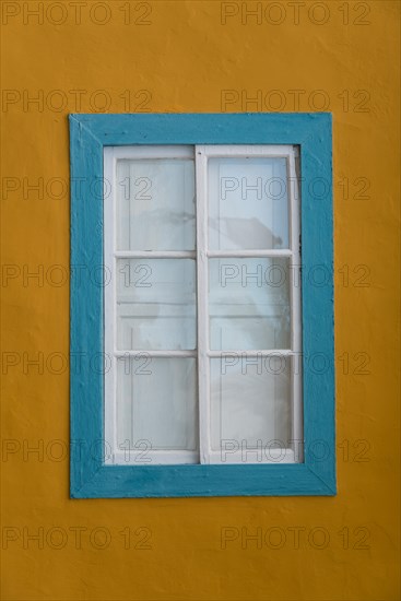 Turquoise coloured window with a yellow facade