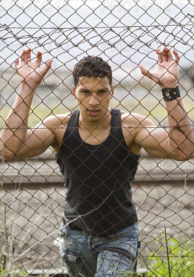 Young man holding onto a fence