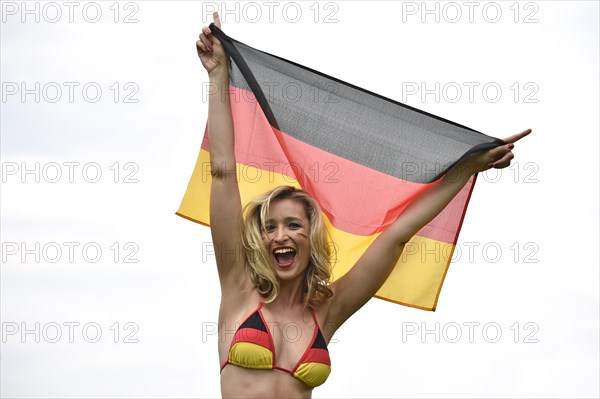 Woman in a bikini in the German national colours holding the national flag of Germany