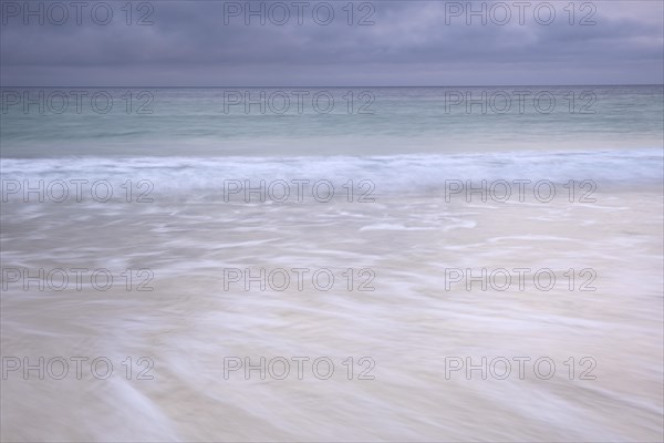 Spray and waves running on a sandy beach