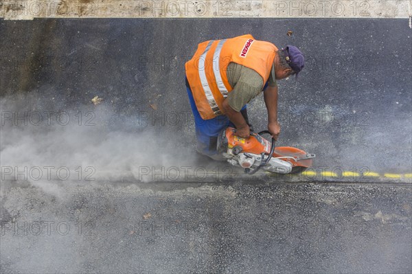 Road construction worker operating a disc cutter