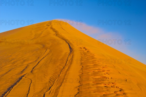 Wind blowing fine sand over the crest of a sand dune