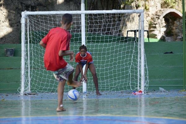 Boy shooting a penalty kick towards a girl in the goal