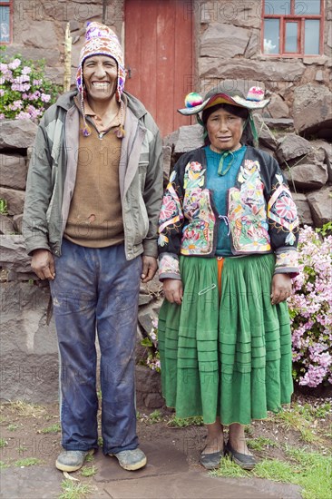 A local man and his wife standing in front of their house