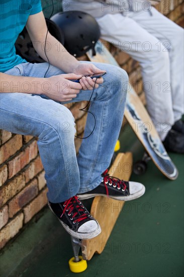 Two teenage boys sitting on a brick wall