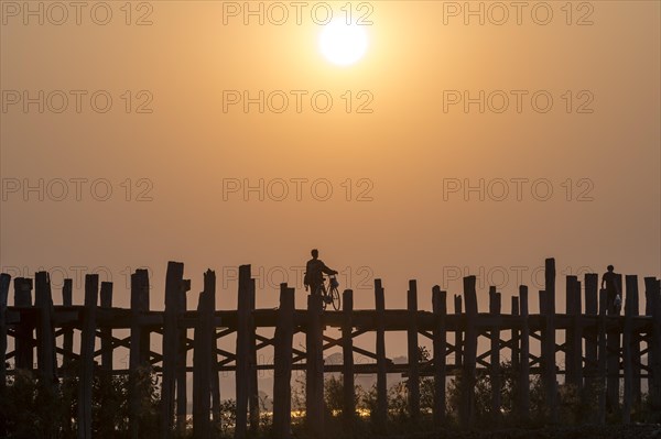 Man riding a bike on a teak bridge