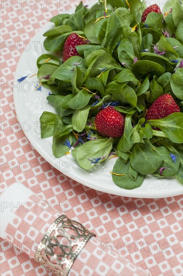 Cornsalad with strawberries and petals served on a plate