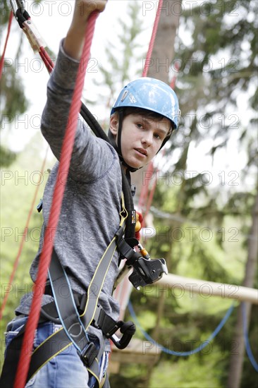 Roped up boy climbing in a climbing park