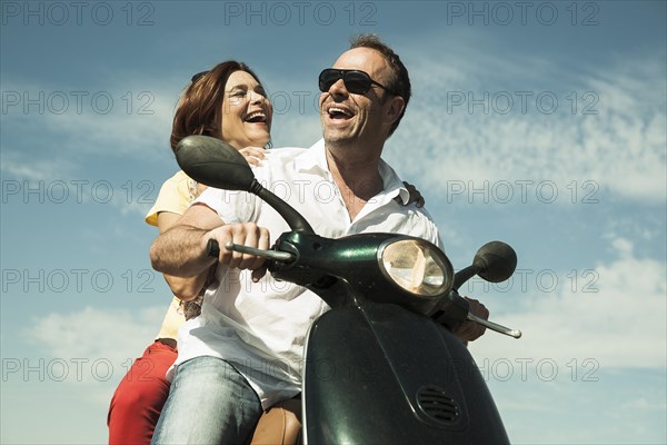 Smiling couple driving with the scooter