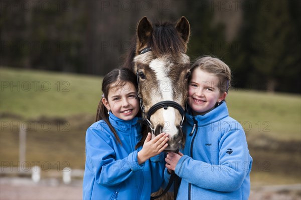 Two girls standing beside a pony