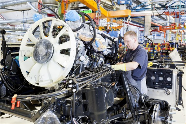 Employee installing the engine and transmission in a chassis at MAN Truck and Bus AG