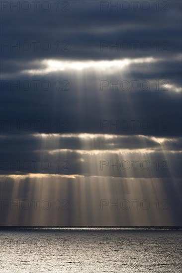 Sun rays shine through dark storm clouds