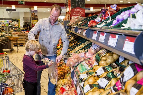 Family shopping with a shopping trolley in the fruit and vegetables department of a supermarket