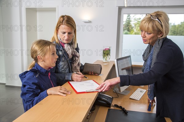Patients filling in a form at the reception of a dental office