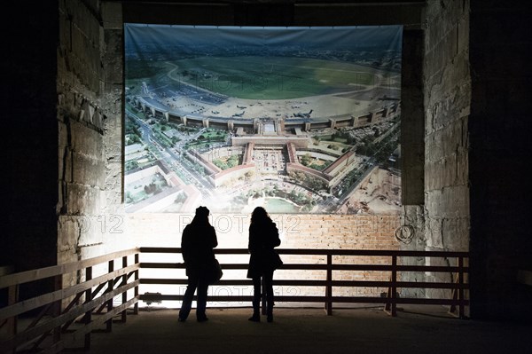 Visitors observing an aerial view of the airport in a large hall