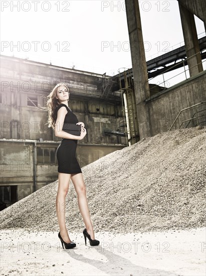 Young woman in black dress standing in front of a cement plant